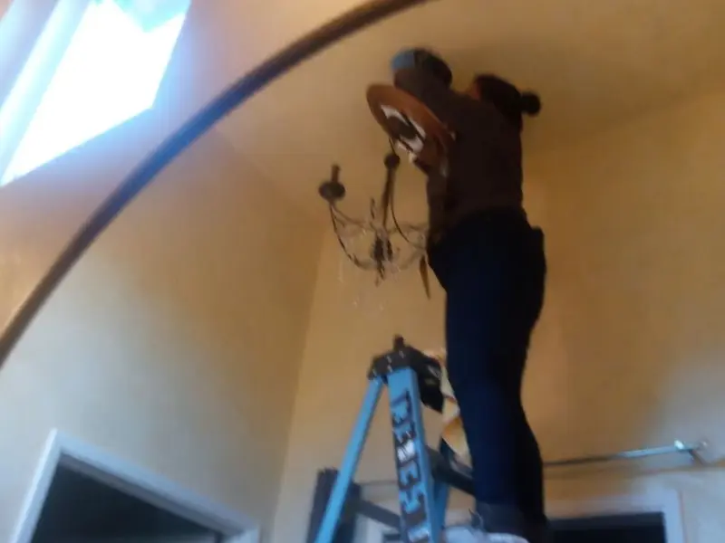 Electrician installing a chandelier in a Morton residence